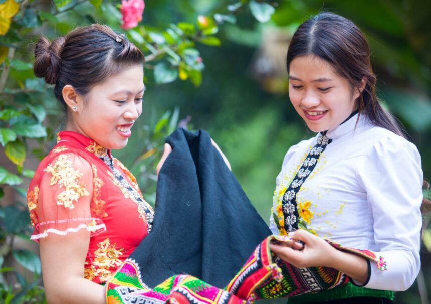 Two Vietnamese women look at embroidered fabric