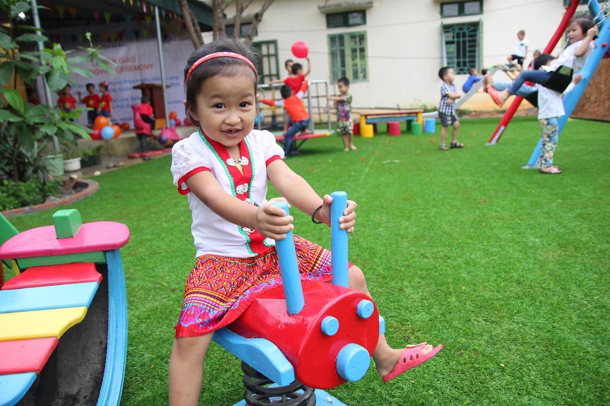 Vietnamese girl playing on playground equipment - Action on Poverty