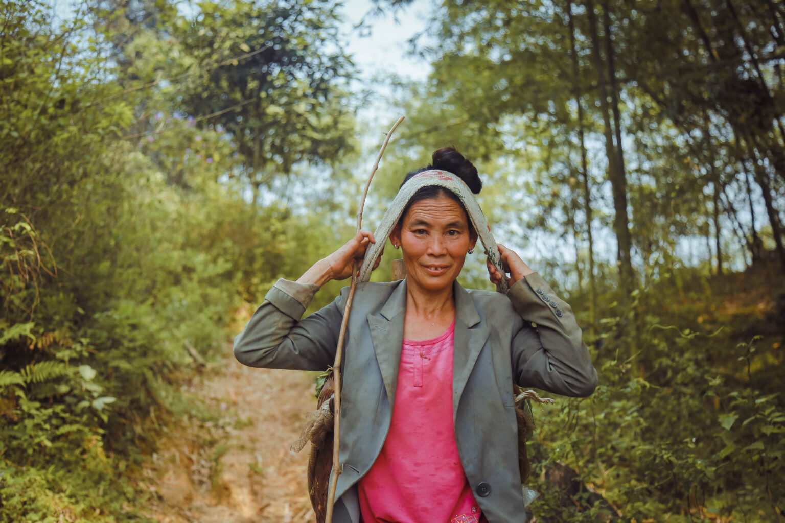 Vietnamese woman walking along forest path carrying produce - Action on Poverty