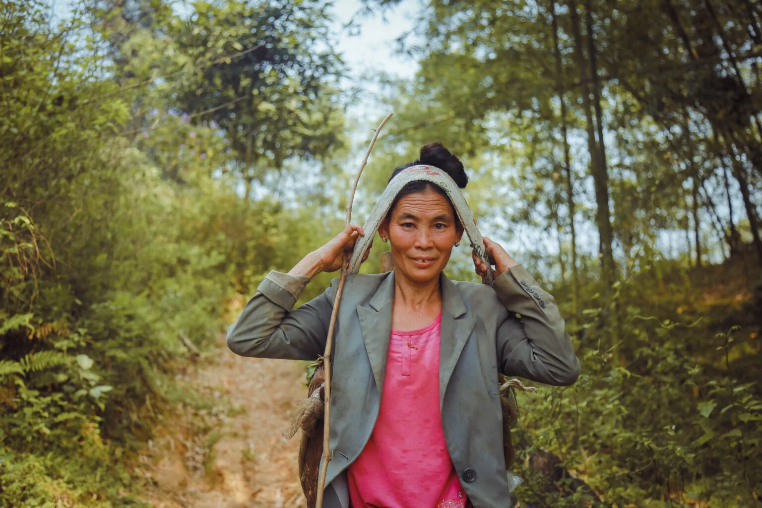 Vietnamese woman walking along forest path carrying produce - Action on Poverty