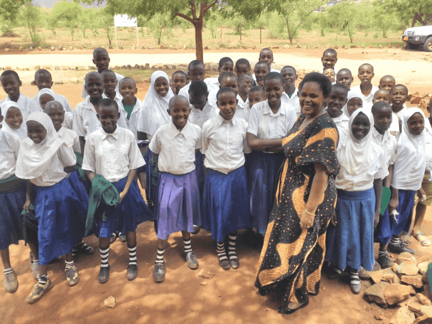 Smiling students in uniform pose with their teacher