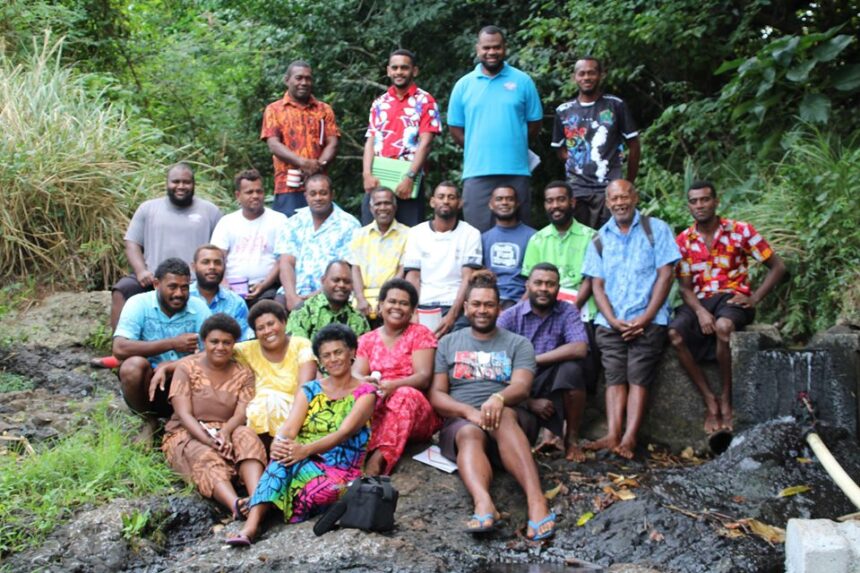 Representatives from water committees pose for a group photo next to a stream