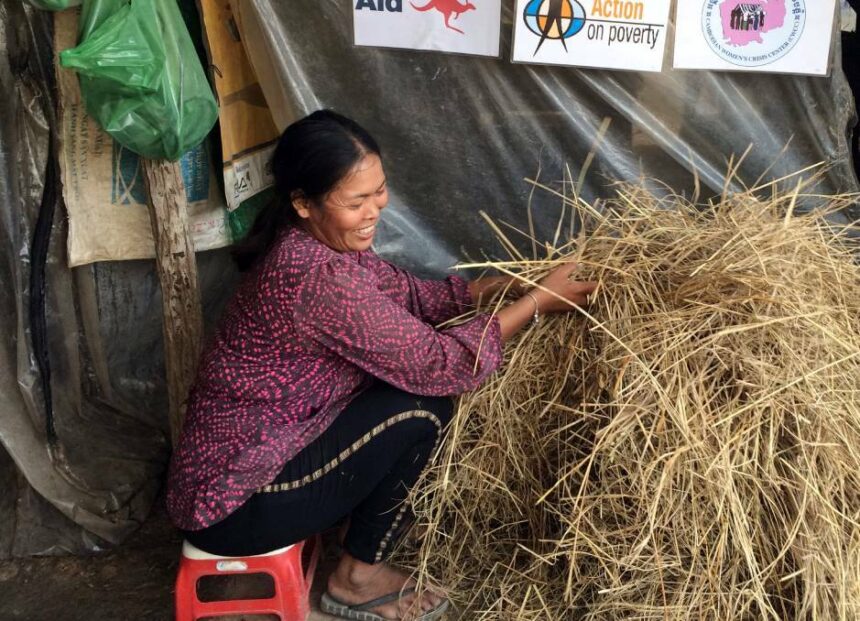 Phan sits on a stool while sorting through hay