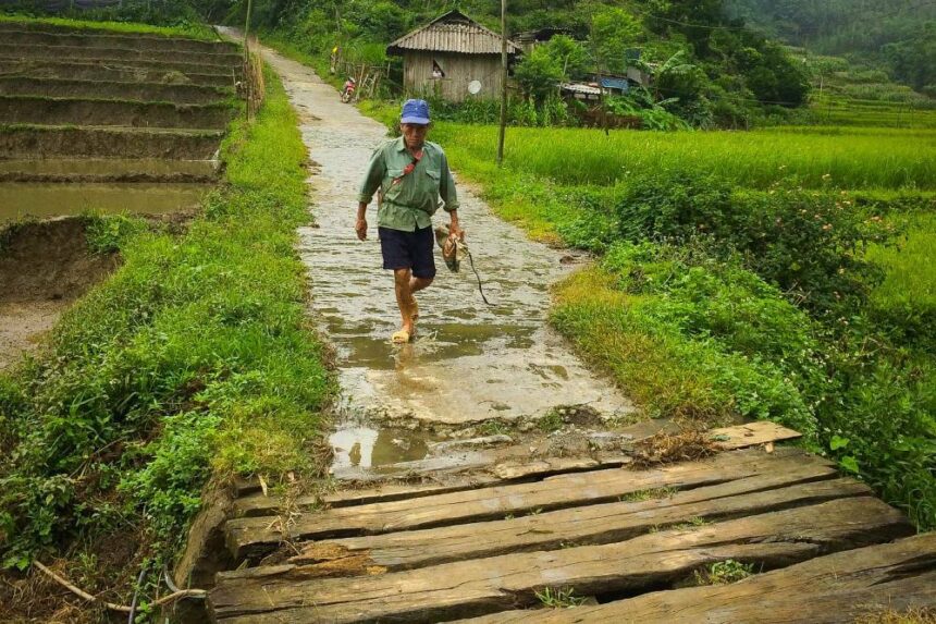 A man walks down a narrow road in a rural village in Vietnam