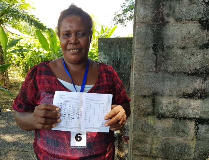 A woman holds up a booklet from her savings group