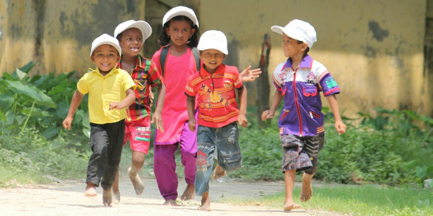 Children in brightly coloured clothing smiling and running together